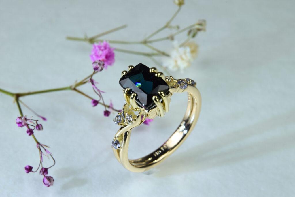 ブルートルマリンを中央に配し、サイバーパンク調の石座と植物モチーフの装飾が特徴のゴールド婚約指輪 OR-1868