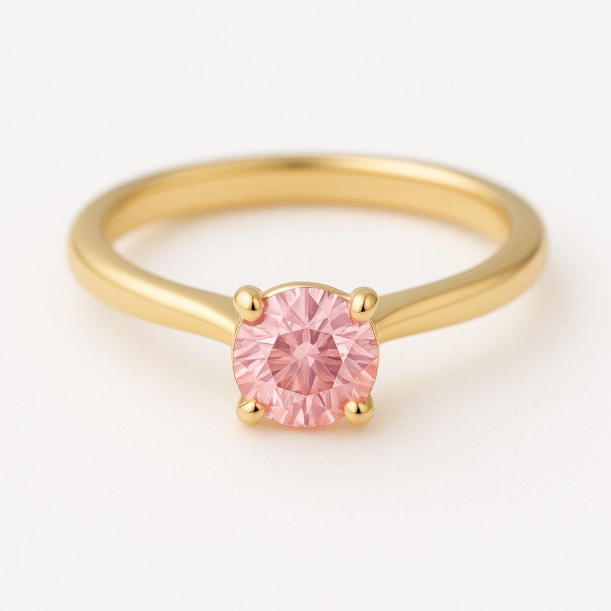 ゴールド色のリングにピンク色のラウンドストーンを留めた婚約指輪