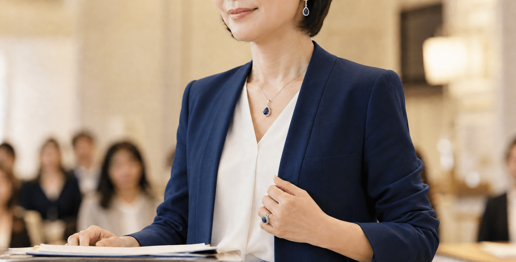 紺のジャケットを着て、人前に立つ準備を整える女性経営者