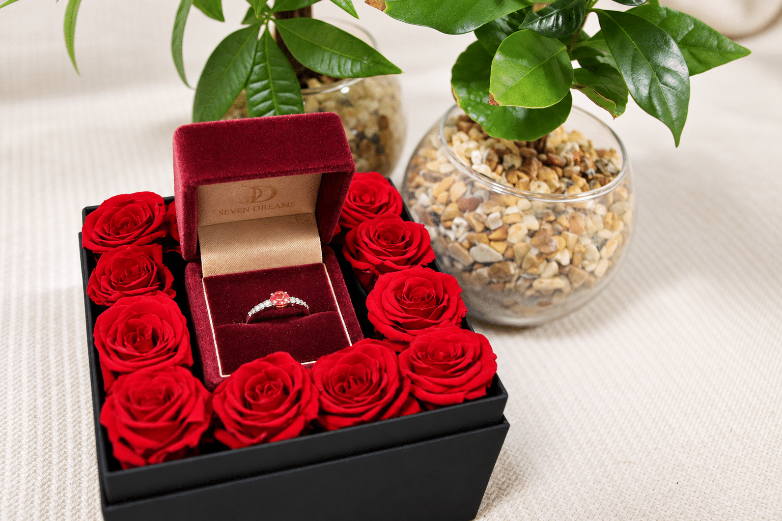 赤いバラに囲まれたリングケースに収めた婚約指輪